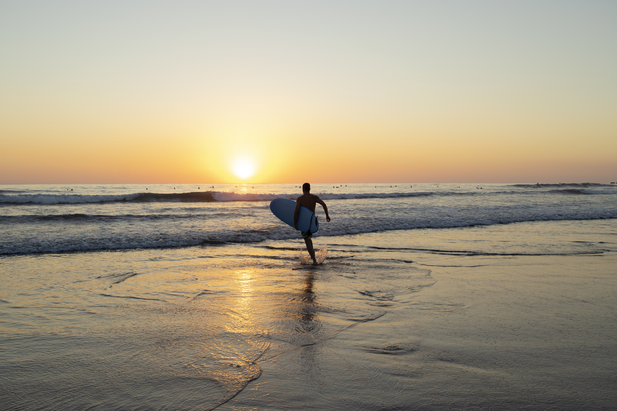 surfer running to catch a sunset wave