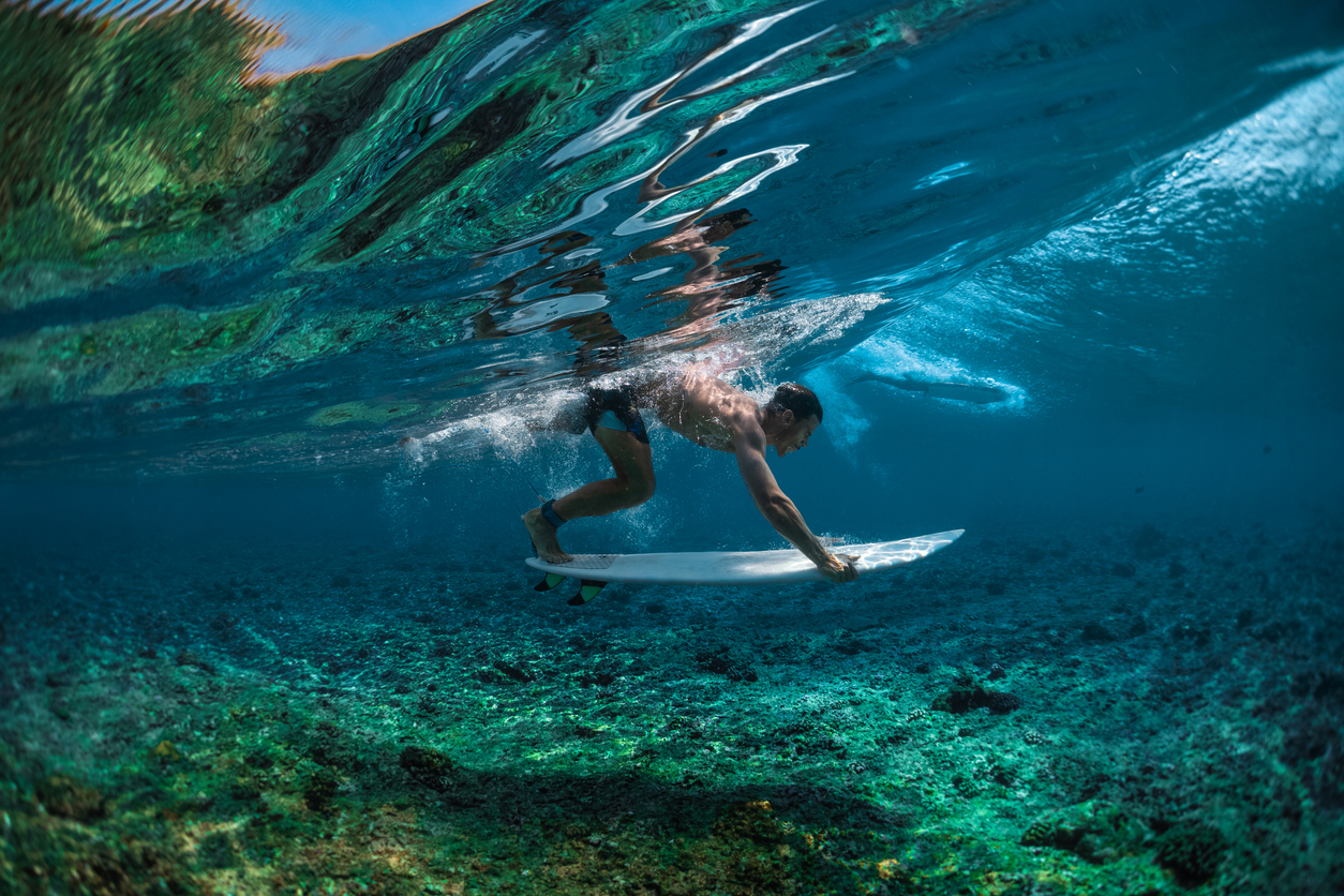Surfer Duck Divers over Surfing Reef